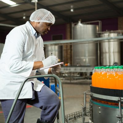 Male worker checking bottles in juice factory Male worker checking bottles in juice factory